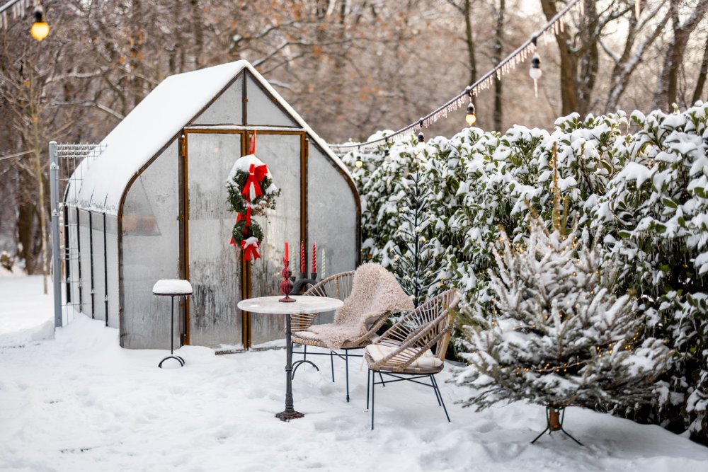 eingeschneites Gewächshaus mit winterlicher Dekoration