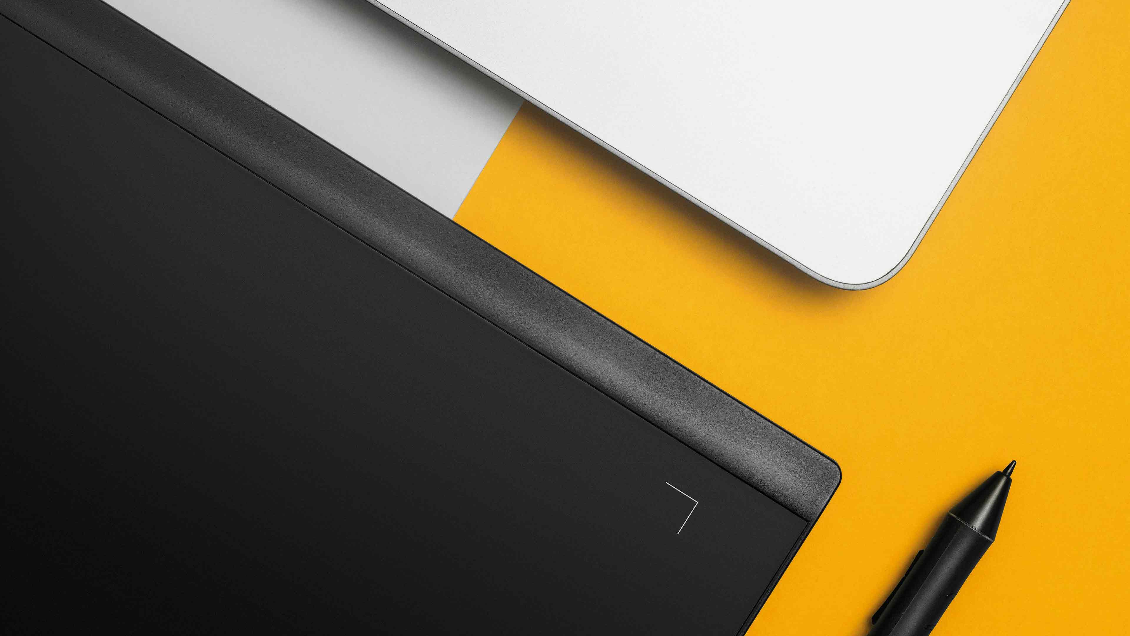 schwarzes und weißes Tablet mit schwarzen Stift auf weiß-gelben Hintergrund