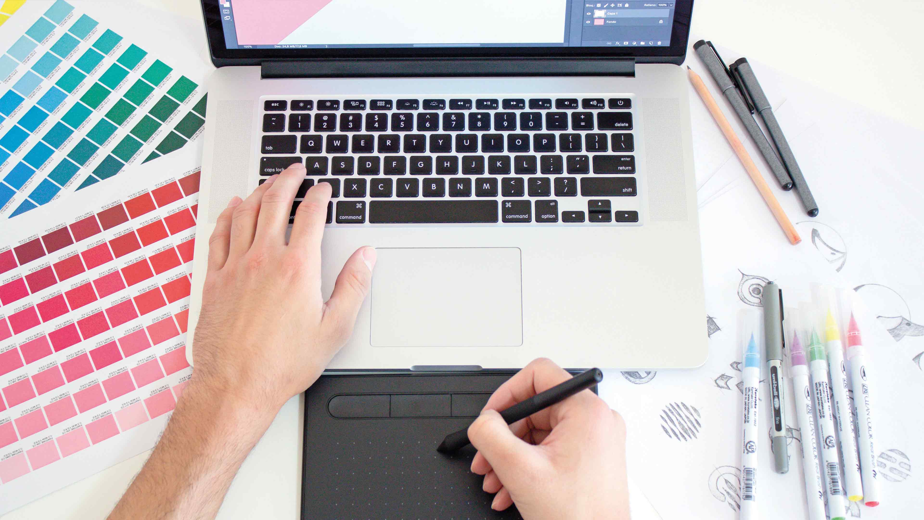Person arbeitet mit schwarzem Schreibpad und Stift an Laptop