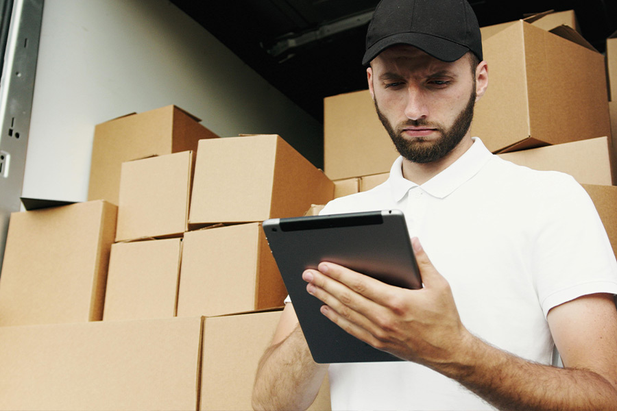 Mann mit Tablet vor Kartons