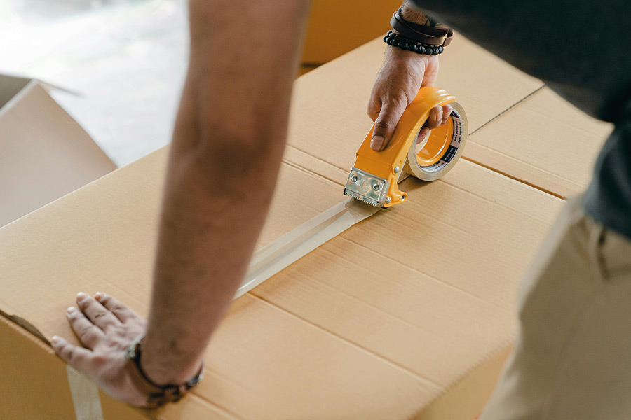 Person klebt großes Packet mit Klebaband zu