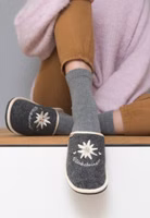 Adelheid Glücksbringer Pantoffel ✓ Edelweiss-Stickerei ✓ made in Portugal ✓ Wollfilz mit Recycling Anteil ein Paar graue Filzpantoffeln mit weiß- und cremefarbender Edelweiß-Stickerei und Glücksbringer Schriftzug, helle Einfassung