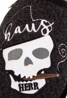 Hausherr Filzpantoffel von Adelheid Nahaufnahme Stickerrei Nahaufnahme einer weißer Totenkopfstickerei, brauner Zigarre im Mund und Hausherr-Schriftzug auf schwarzem Filz