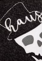 Hausherr Filzpantoffel von Adelheid Nahaufnahme Nahaufnahme einer weißer Totenkopfstickerei, brauner Zigarre im Mund und Hausherr-Schriftzug auf schwarzem Filz