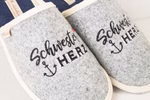 ein grauer Pantoffel mit schwarz roter Stickerrei und Schwester Herz Schriftzug Nahaufnahme
