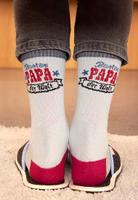 getragen von hinten fotografiert ein Paar hellgraue Sport-Socken mit dunkelgrau abgesetztem Bündchen sowie Zehenbereich und dunkelrot abgesetztem Fersenbereich. Im oberen Knöchelbereich in blau und rot der Bester Papa der Welt Schriftzug
