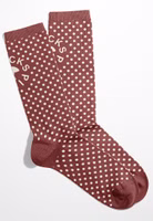 ein Paar dunkelrote Glückspilz Socken mit weißen Punkten, uni rot abgesetztem Bündchen-, Fersen- und Zehenbereich sowie oberhalb des Knöchels dem Motiv eines Fliegenpilzes und dem Schriftzug Glückspilz