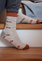 sitzend auf Treppenstufen mit einem Paar graubeigen Sportskanone Socken mit Fahrrad-Allover in grau und rostbraun. Dazu grau und rostbraun abgesetzte Bündchen, Fersen- und Zehenbereiche
