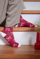 sitzend auf Treppenstufen mit einem Paar bordeaux-farbene Herzensdame Socken mit Herzchen und Schleifen-Allover sowie abgesetzte Bündchen, Fersen- und Zehenbereiche in weiß
