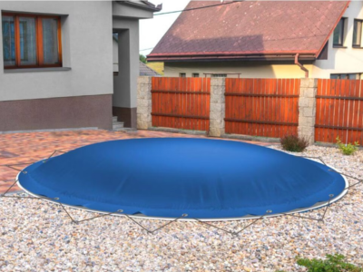 Abdeckung in blau auf einem Rundpool vor einem Haus